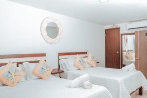 two beds in a room with white and orange pillows at APARTAHOTEL BEIRUT INN in San Andrés