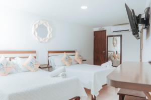a bedroom with two beds with white sheets and blue pillows at APARTAHOTEL BEIRUT INN in San Andrés