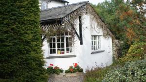 a white house with flowers in front of it at Wheelgate in Torver
