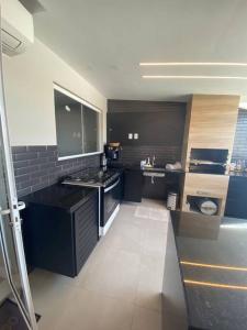 eine große Küche mit schwarzen Arbeitsflächen und einem Waschbecken in der Unterkunft Linda e luxuosa cobertura na praia do Forte, Cobertura Sol De Verão in Cabo Frio