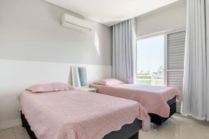 zwei Betten in einem Zimmer mit Fenster in der Unterkunft Linda e luxuosa cobertura na praia do Forte, Cobertura Sol De Verão in Cabo Frio