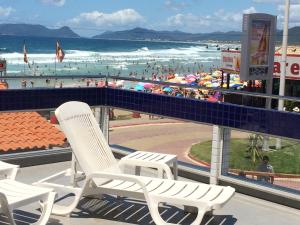 a view of a beach with white chairs and people at Cris Hotel in Florianópolis