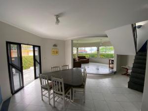 a dining room and living room with a table and chairs at Casa Alto Padrão de Frente ao Mar in Peruíbe