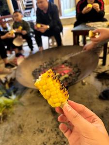 a person holding a piece of corn on a stick at HaPu Homestay Lô Lô Chải in Loung Co