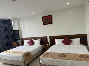 a bedroom with two beds and a picture on the wall at Mạnh Quỳnh Hotel in Tinh Xa