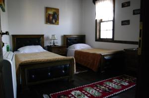 a bedroom with two beds and a window and a rug at Hotel Klea in Berat