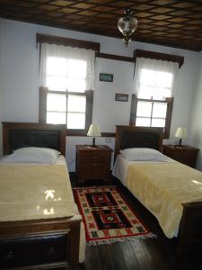 two beds in a room with two windows and a rug at Hotel Klea in Berat