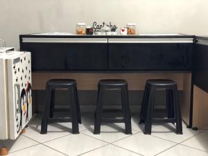 a kitchen with three stools under a counter at Apartamentos Mãe Aparecida do Norte in Aparecida