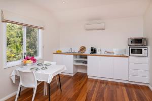 Una cocina con gabinetes blancos y una mesa y sillas blancas. en The Whale Lookout, Eagle Bay, en Dunsborough