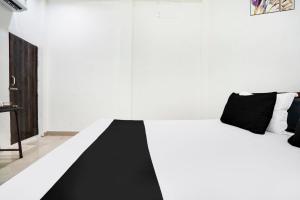 Un dormitorio con una cama blanca con almohadas negras. en Hotel O The Moon, en Bareilly