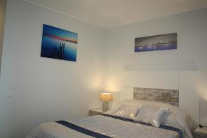 sypialnia z łóżkiem i 2 zdjęciami na ścianie w obiekcie Ventur Flat w Caniço