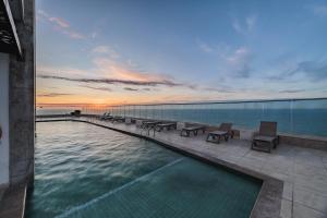 een zwembad met uitzicht op de oceaan bij zonsondergang bij Palmetto Beach by MOME in Cartagena