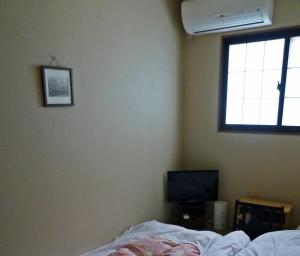 a bedroom with a bed and a window and a television at Guesthouse Engawa in Kyoto