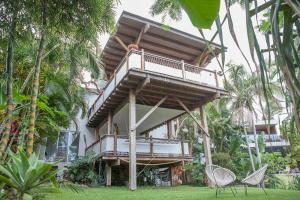 a building with a balcony and chairs in the grass at THE BEACH HAVENS in Emerald Beach
