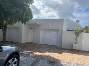 Una casa blanca con dos puertas de garaje y un árbol. en On Musson, en Hermanus 3 fotos más