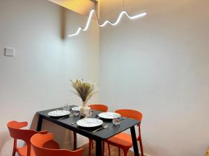 a dining room table with orange chairs and a black table at X - The Thomas Bangsar South Midvalley LRT Kerinchi in Kuala Lumpur +37 photos