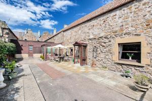 a stone house with a courtyard with a patio at Painters Cottage in Haddington