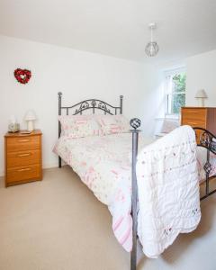 a bedroom with a bed with pink and white sheets at Painters Cottage in Haddington