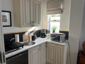Una cocina con gabinetes blancos, un fregadero y un microondas. en On Musson, en Hermanus