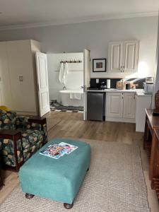 Una sala de estar con una otomana azul frente a una cocina. en On Musson, en Hermanus