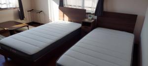 a bedroom with two beds and a desk and a window at Guesthouse Gifu SUAI in Gifu
