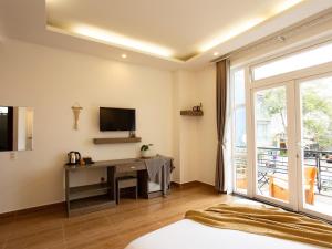 a room with a desk and a tv and a window at K HO DISCOVERY Guest House in Da Lat
