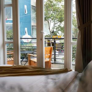 a bedroom with a bed and a view of a balcony at K HO DISCOVERY Guest House in Da Lat