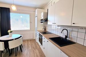 cocina con armarios blancos, mesa y fregadero en Villa Ruths Stay Torni, en Kouvola
