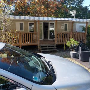 波讷地区圣朱利安Mobil home 8 personnes 3 chambres的一座带门廊的房子,前面有一辆汽车