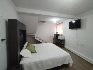 a bedroom with a white bed and a flat screen tv at Hotel El Balcón in Zacatlán