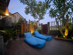 a patio with blue pillows and trees and a fence at Mahesa House by SHM in Ubud