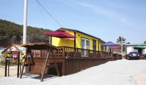 a yellow house with a playground and an umbrella at Cheonripo Eunhasoo Pension in Taean