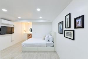 a white bedroom with a bed and a flat screen tv at Sellin Onsu Swimming Pool Pension in Gapyeong