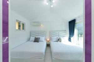 two beds in a room with purple and white walls at Sellin Onsu Swimming Pool Pension in Gapyeong