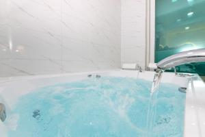 a bath tub with blue water pouring from a faucet at Sellin Onsu Swimming Pool Pension in Gapyeong
