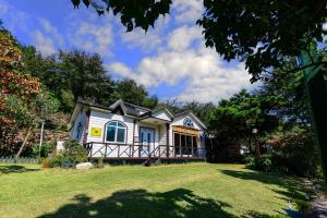 a white house with a porch on a lawn at Giltara HaengWoon Pension in Gapyeong +25 photos