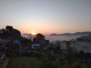 a misty sunrise with a house in the foreground at สิรีรินทร์ ภูหมอก in Khao Kho +42 photos