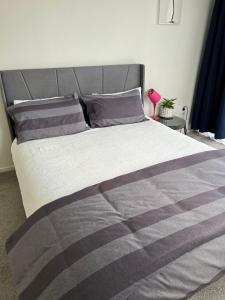 a bedroom with a bed with a gray and gray comforter at Totara Vale, Free Coffee, parking and wifi, near Glenfield Mall and highway 18,1 in Auckland