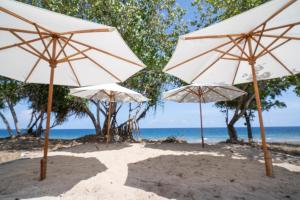 Eine Gruppe von Sonnenschirmen an einem Strand mit Blick auf das Meer in der Unterkunft Sofanda Resort & Dive in Nangamiro