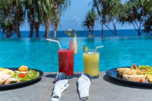 Zwei Teller mit Essen und Getränken neben einem Pool in der Unterkunft Sofanda Resort & Dive in Nangamiro