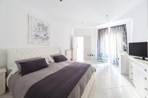 biała sypialnia z dużym łóżkiem i telewizorem w obiekcie Veneto Excelsior Suite w Rzymie