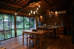 a kitchen with a wooden table with chairs and a large window at Shanti Life Wooden House in Pemuteran