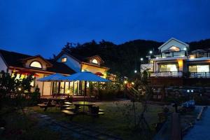 a house with a table and an umbrella at night at Pension on the Sea Shore in the Bosom Department Byeonsanbando in Buan