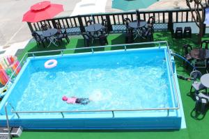 a person swimming in a swimming pool with an umbrella at Byeonsanbando Dongjin Castle Pension in Buan
