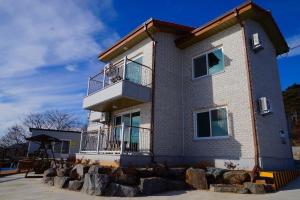 a large brick building with a balcony and rocks at Byeonsanbando Badajeonmangdae Pension in Buan +7 photos