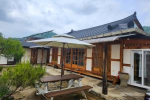 a wooden building with an umbrella and a bench at Jeonju Hanok-an hanok an Pension in Jeonju +9 photos