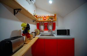 una pequeña cocina con armarios rojos y fregadero en Jeonju Hanok Geugot Stay, en Jeonju 8 fotos más