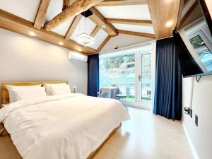 a bedroom with a white bed and a large window at Byeoldul Private Pension in Jeonju