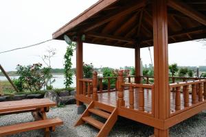 a wooden gazebo with two benches and a lake at Buan Byeonsanbando Haejoeum Pension in Buan