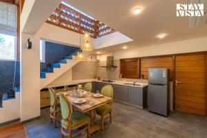 シムラーにあるStayVista at Nook - Elysium Estate 2 BR Cottage with Hill View, Lawnのテーブルと冷蔵庫のあるキッチンとダイニングルーム